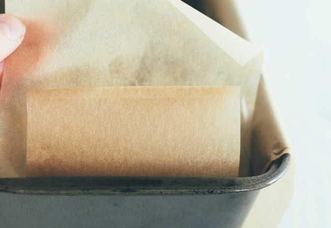 Close up of lining a loaf pan with parchment