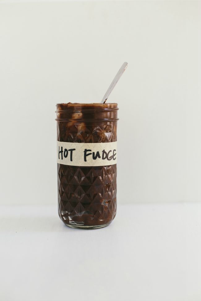 homemade hot fudge in a glass jar, with spoon sticking out of it