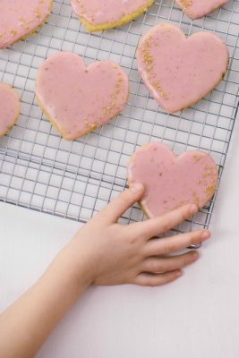 child reaching for a heart shaped cut out cookies