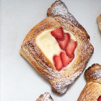 Cream-Filled Danish with strawberries on parchment paper