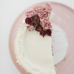 white chocolate cake with white chocolate frosting on pink plate