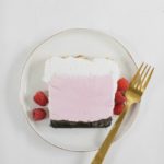 raspberry ice cream cake on a white plate with gold spoon