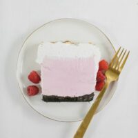 raspberry ice cream cake on a white plate with gold spoon
