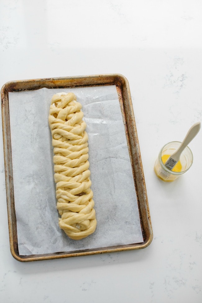 Danish Braid on a Sheet Pan Next to a Cup of Egg Wash | The Vanilla Bean Blog