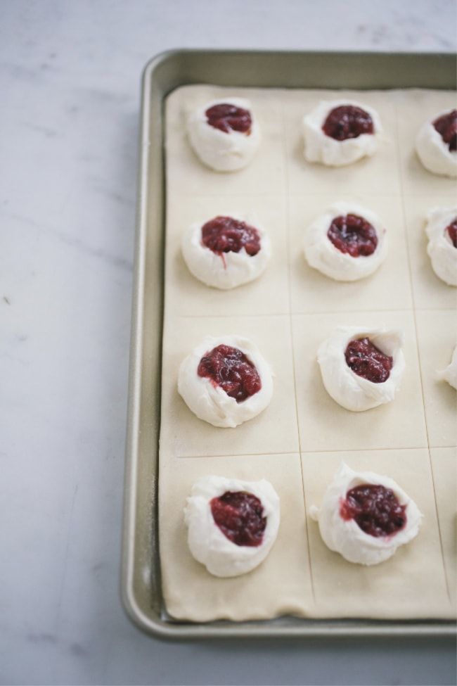 filling puff pastry sheets with jam on a baking sheet to make Danish Slab Pie