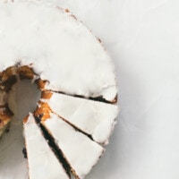 Blueberry Orange bundt cake with glaze, a few slices cut out of it.