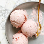 strawberry rhubarb ice cream in a dish with gold spoon