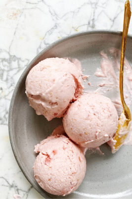 strawberry rhubarb ice cream in a dish with gold spoon