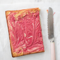 raspberry white chocolate brownies on white parchment paper with pink knife to the right