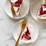 no bake cheesecake slices on white plates with gold forks