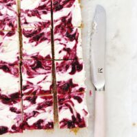 no-bake cheesecakes bars with cranberries, sitting next to a pink knife
