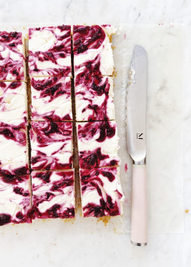 no-bake cheesecakes bars with cranberries, sitting next to a pink knife