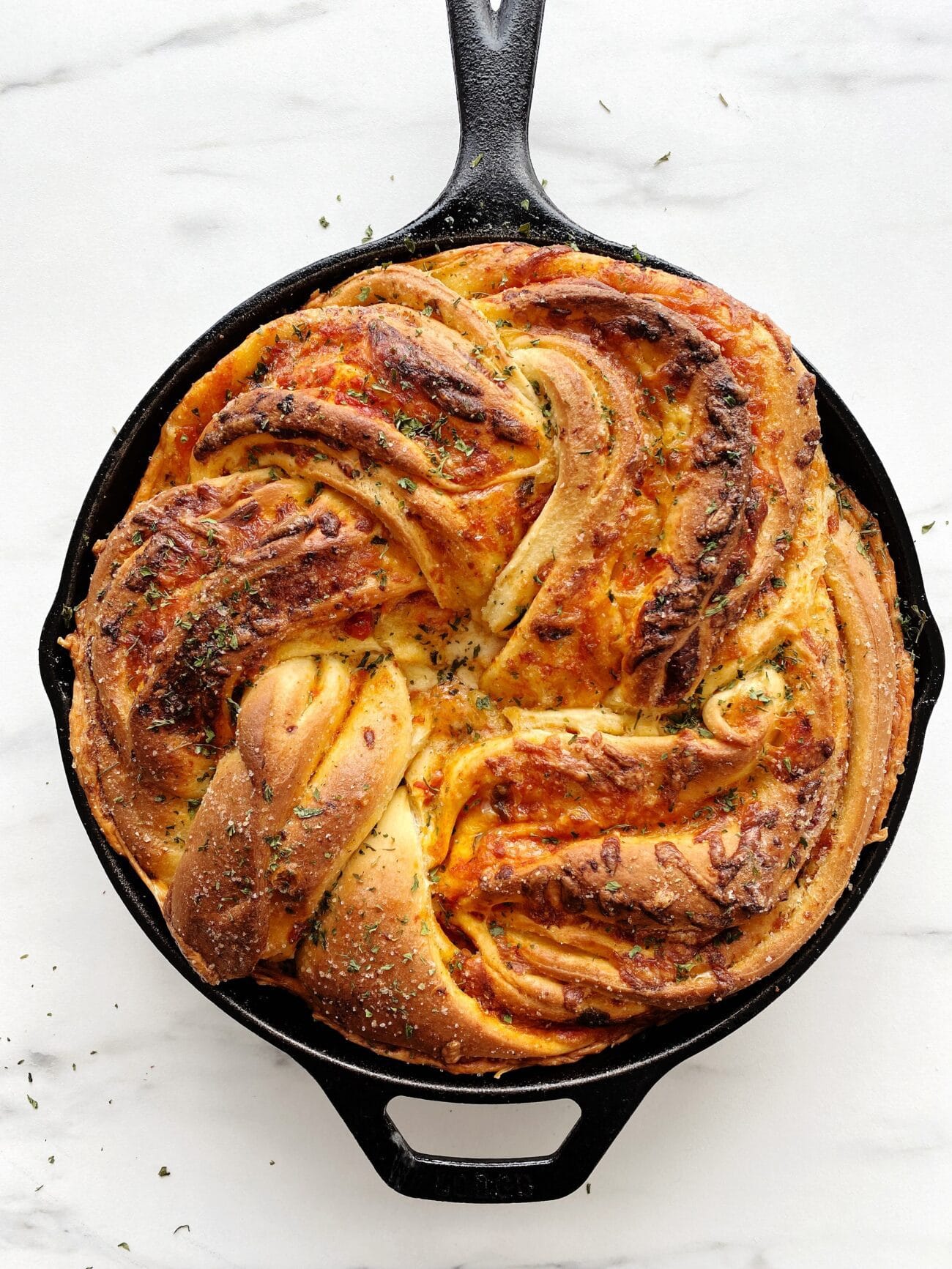 Freshly made loaf of round bread in the black cast iron oven pan