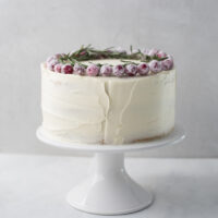 white chocolate cake with sugared cranberries on marble cake stand