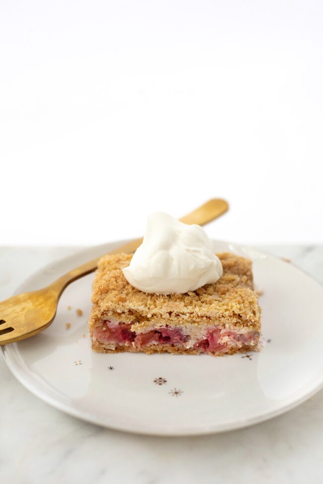rhubarb bars on a plate with a dollop of whipped cream