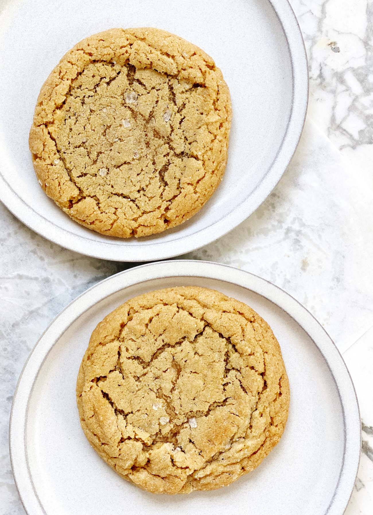 two peanut butter cookies on white plates