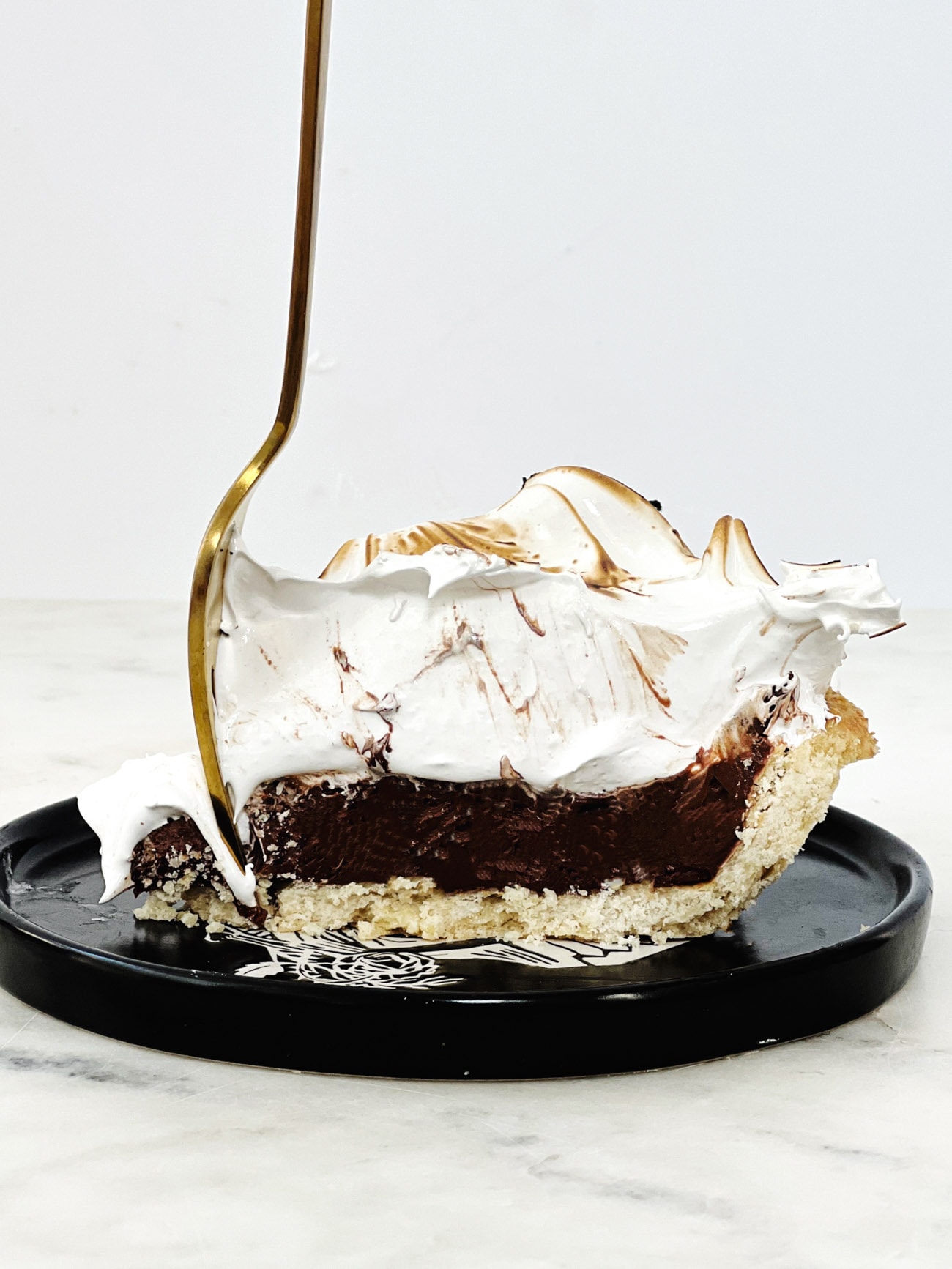 chocolate meringue pie with gold fork in it