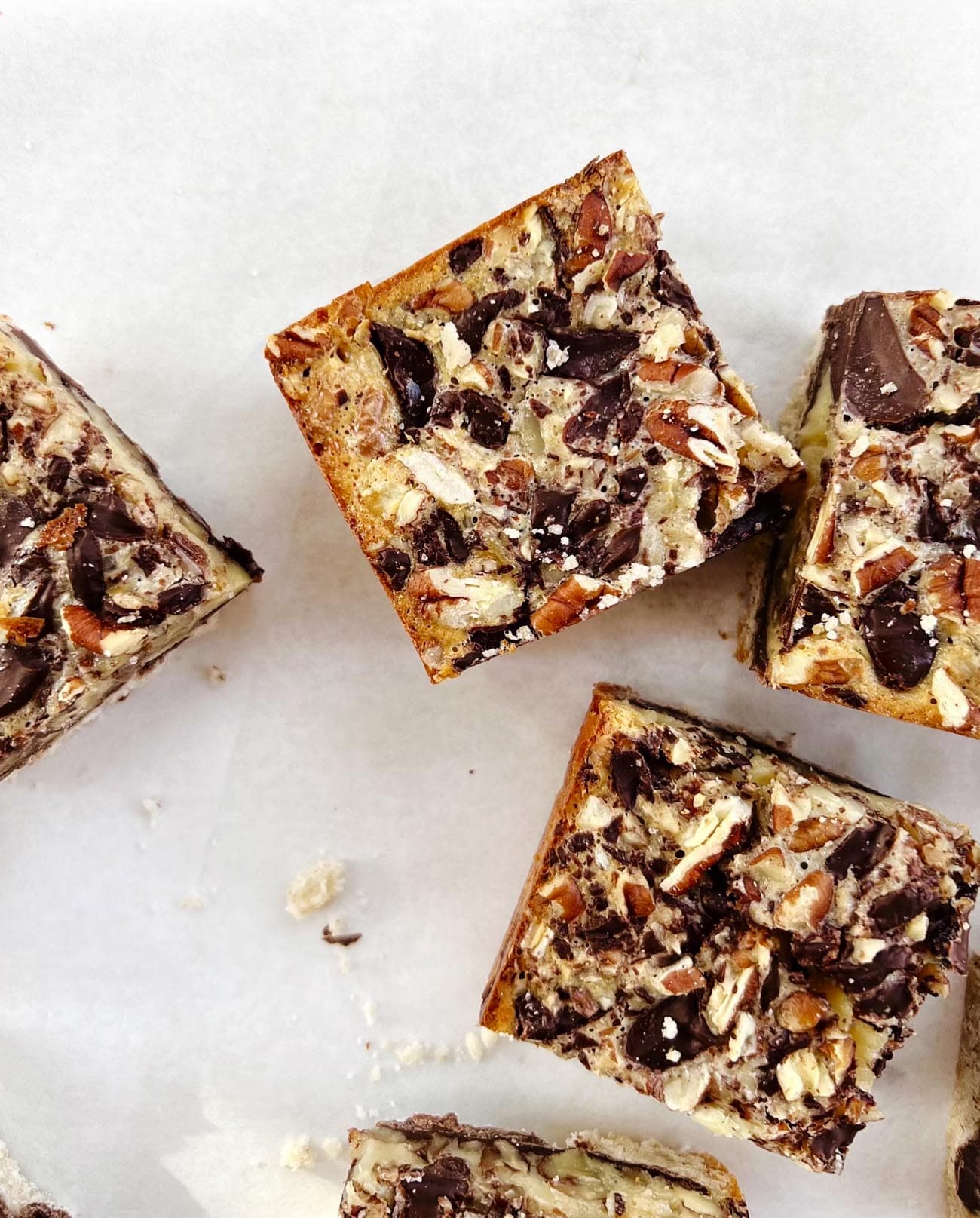 chocolate pecan pie bars on white parchment paper