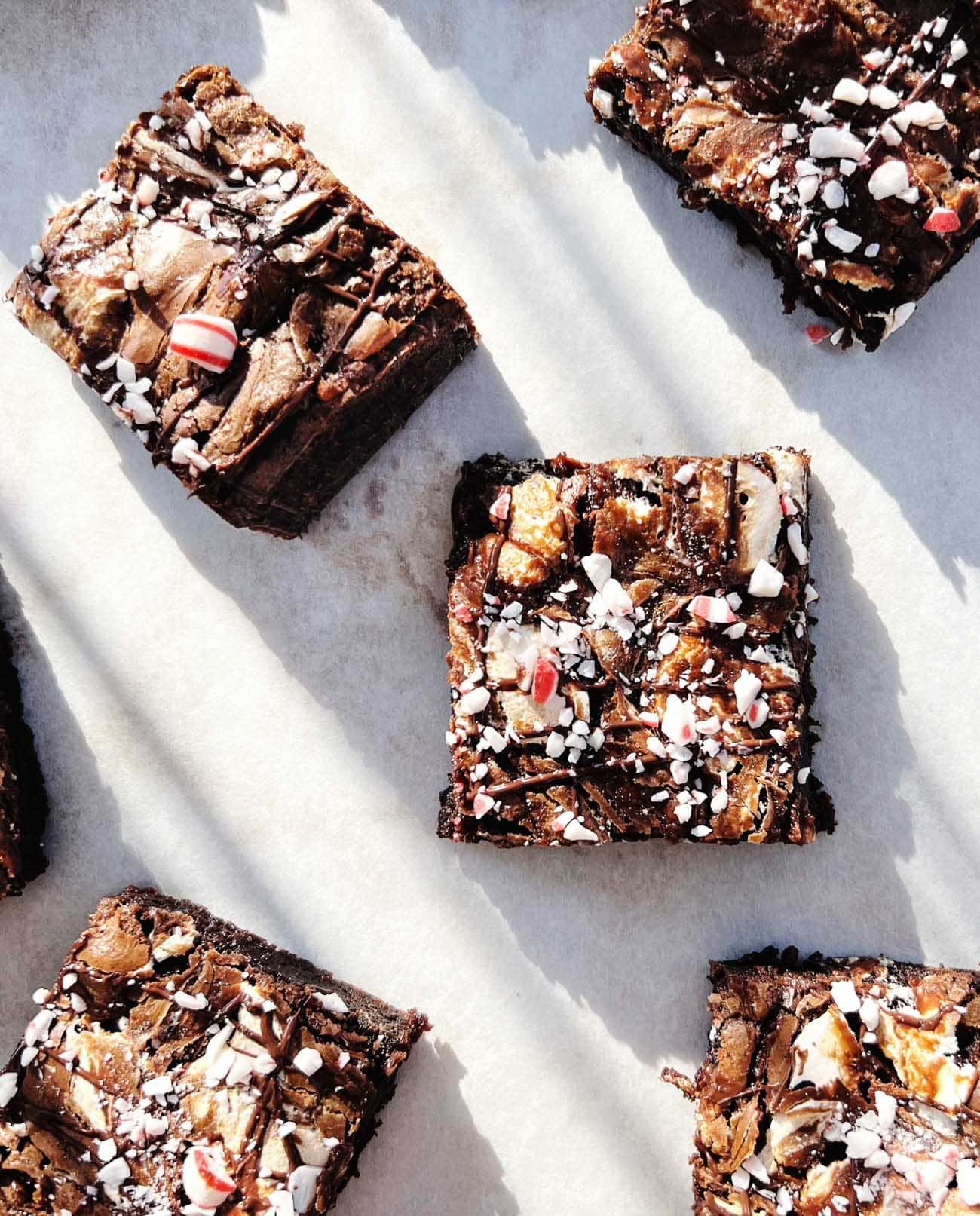 peppermint hot chocolate brownies cut into squares on white parchment paper