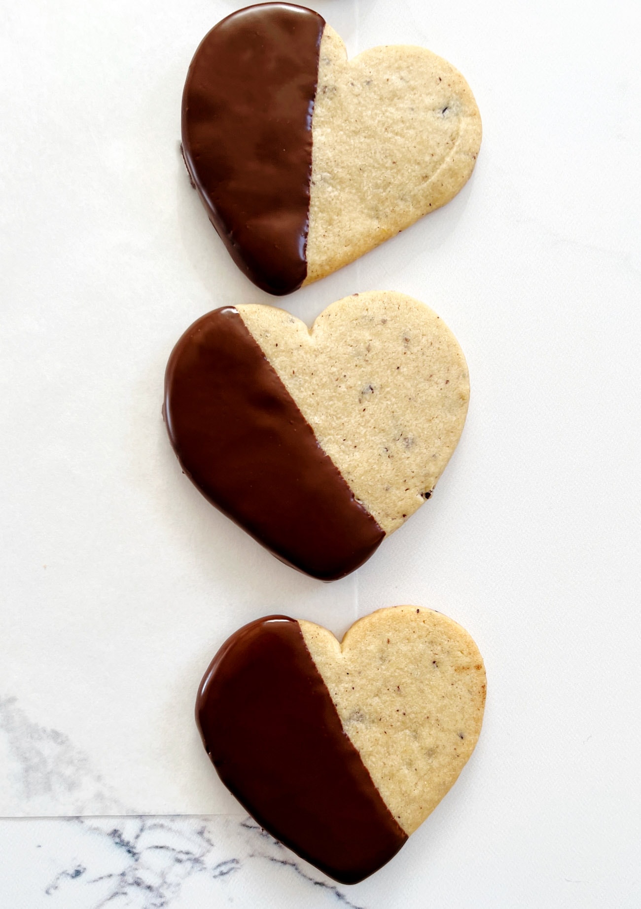 chocolate dipped heart cut out cookies on parchment