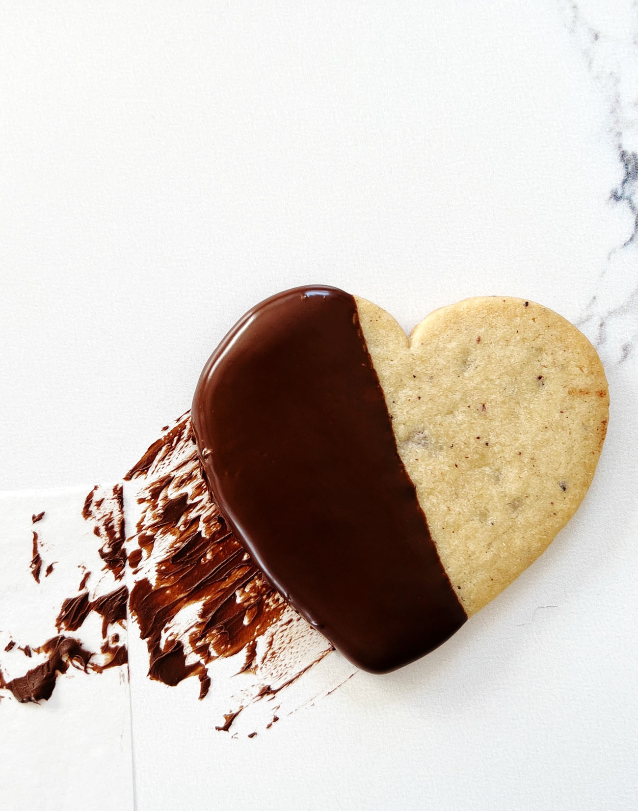 chocolate dipped cacao nib cookies on parchment