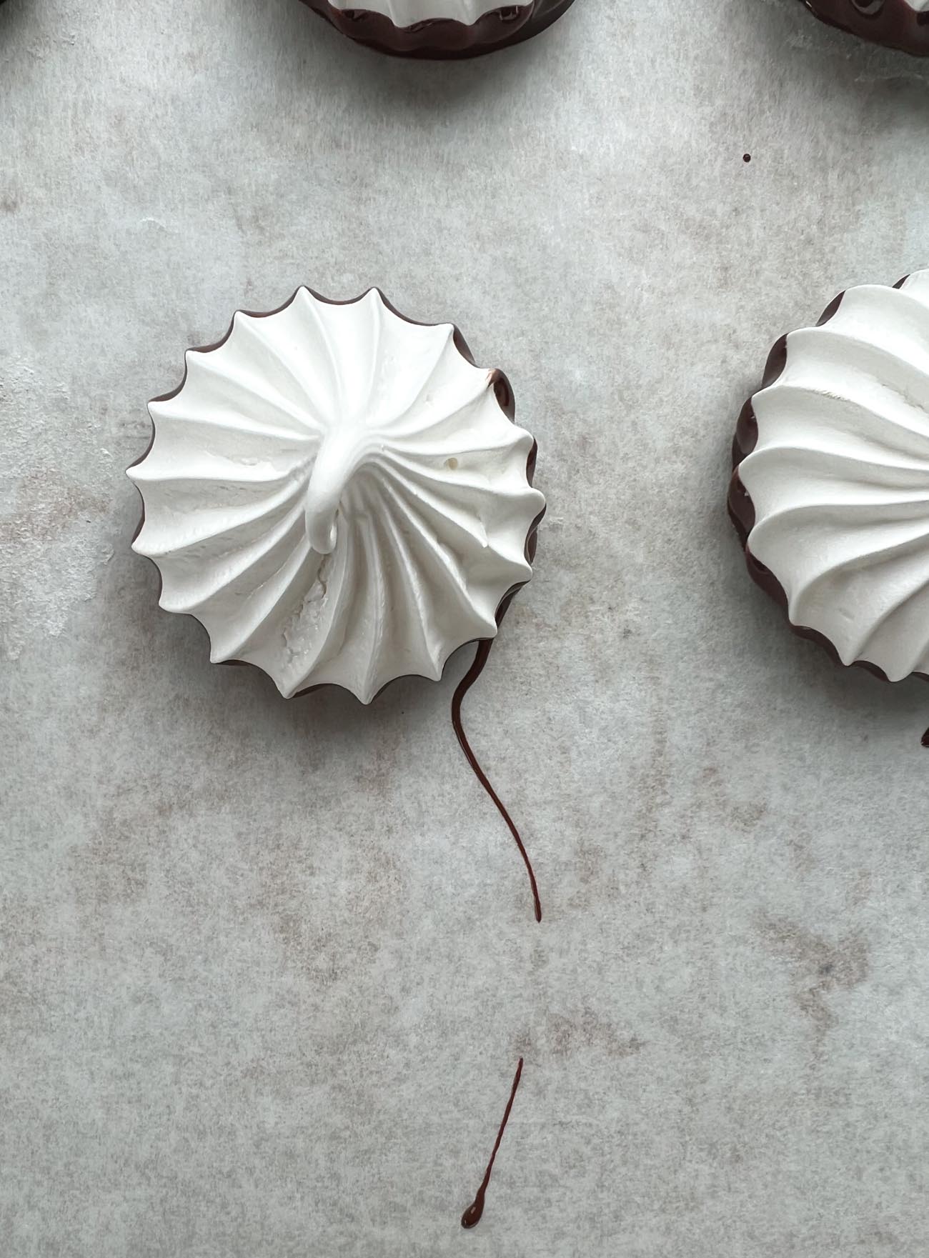 chocolate dipped meringue cookies on parchment paper