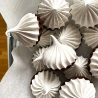 chocolate dipped meringues on parchment paper