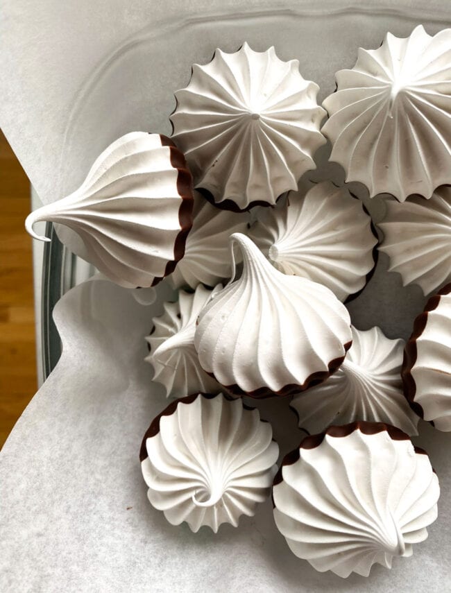 chocolate dipped meringues on parchment paper