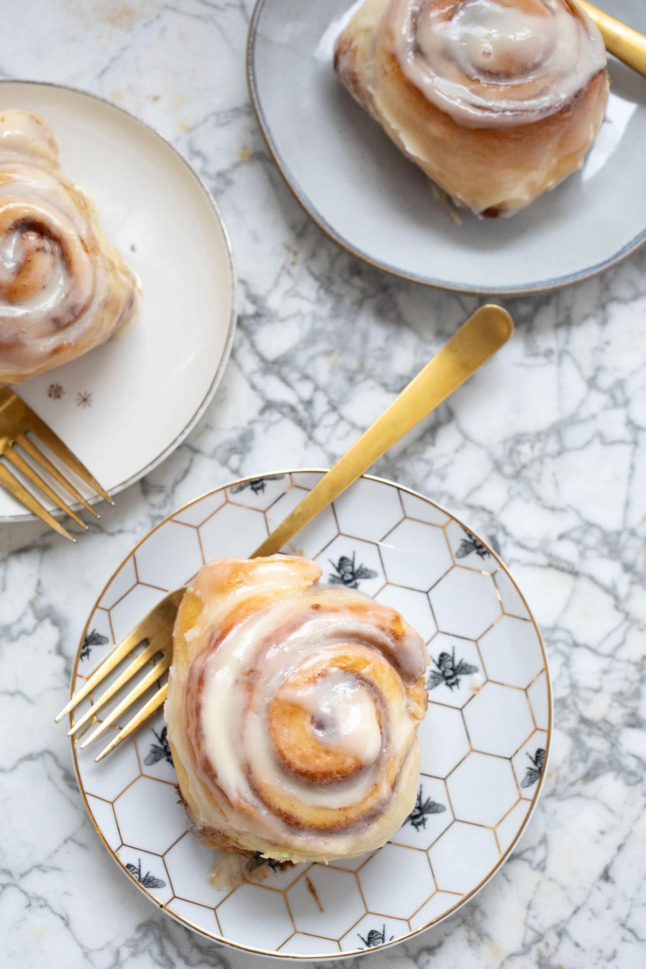 buttermilk cinnamon rolls on plates with gold forks