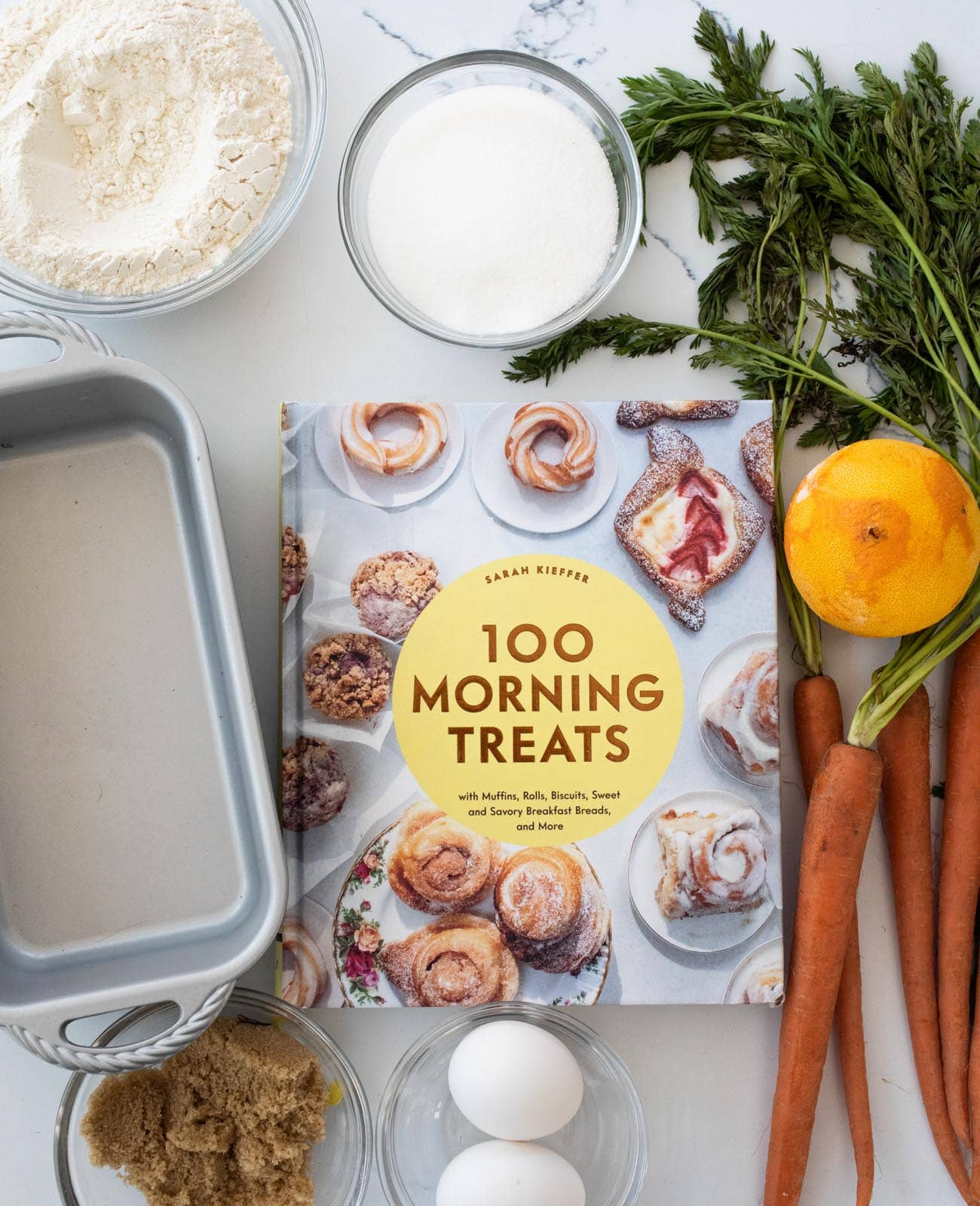 baking ingredients surrounding cookbook