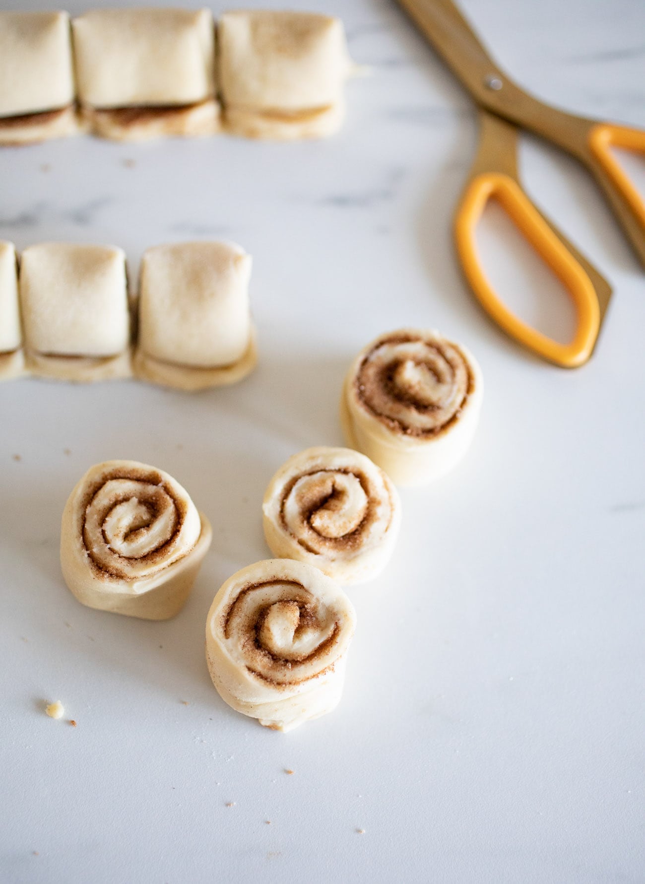 using a scissor to cut mini cinnamon rolls