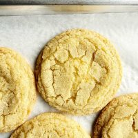 Chewy Lemon Sugar Cookies on parchment paper with cracked surface.